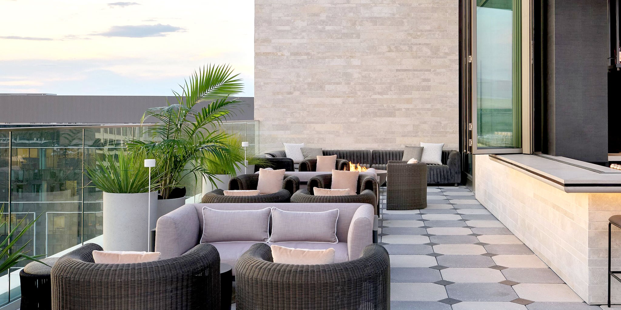 Halo STRATA limestone exterior stone wall panels on a modern outdoor terrace with patterned stone flooring and lounge seating