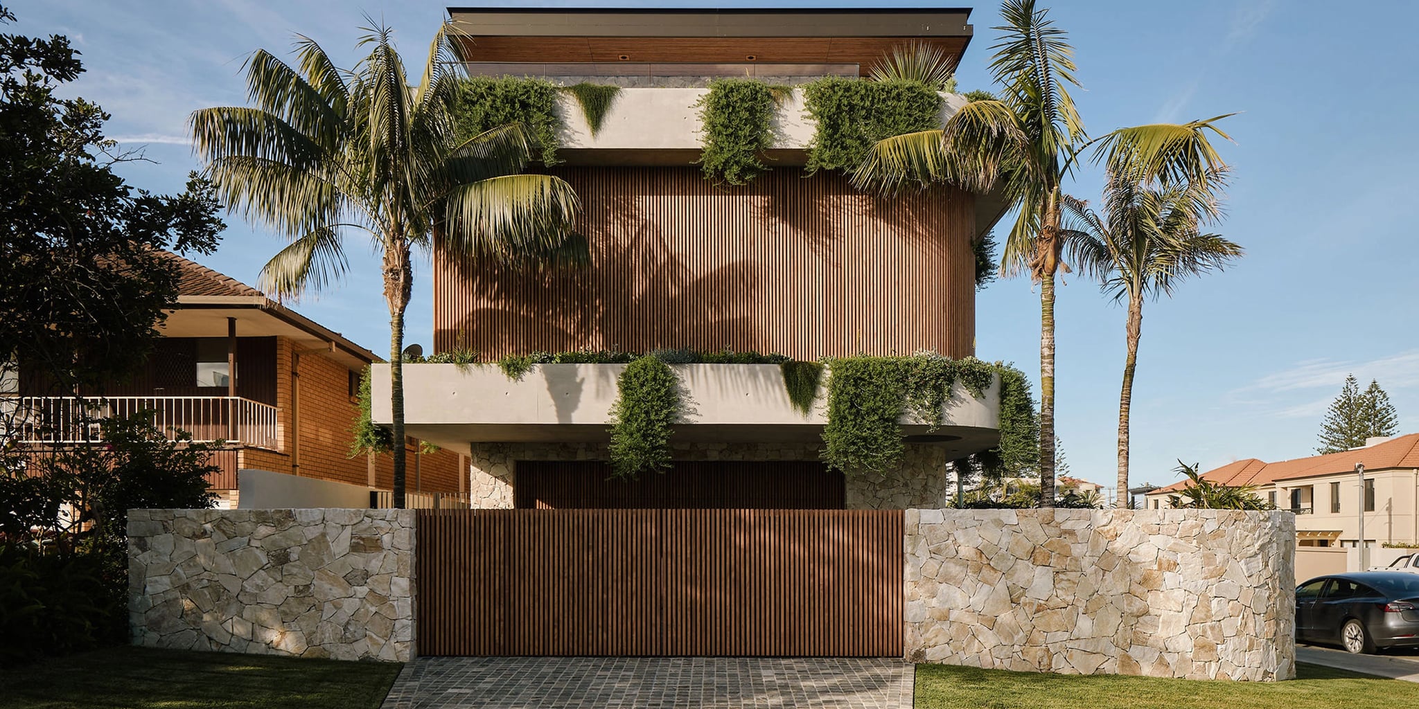 Sonoma exterior stone wall panels on a modern residence with tropical landscaping and a curved stone entry wall