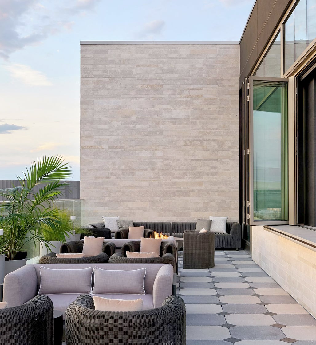 Halo STRATA large format modern limestone veneer on an outdoor terrace wall with lounge seating and patterned stone flooring