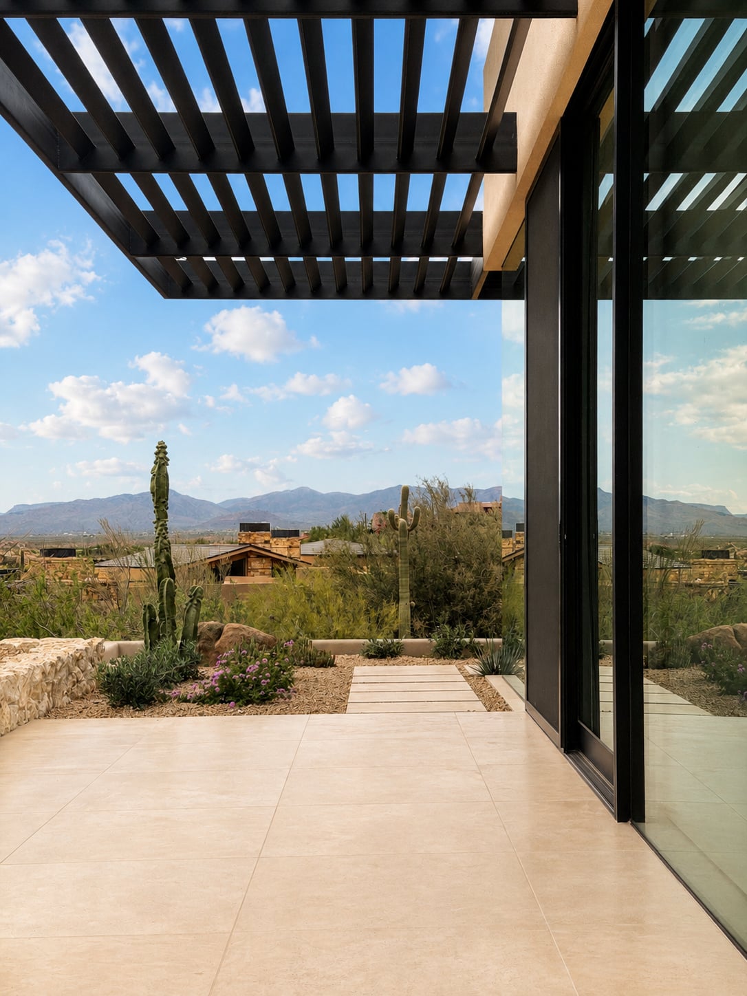 Dune Cashmere limestone flooring on a modern exterior patio with glass walls and mountain views.