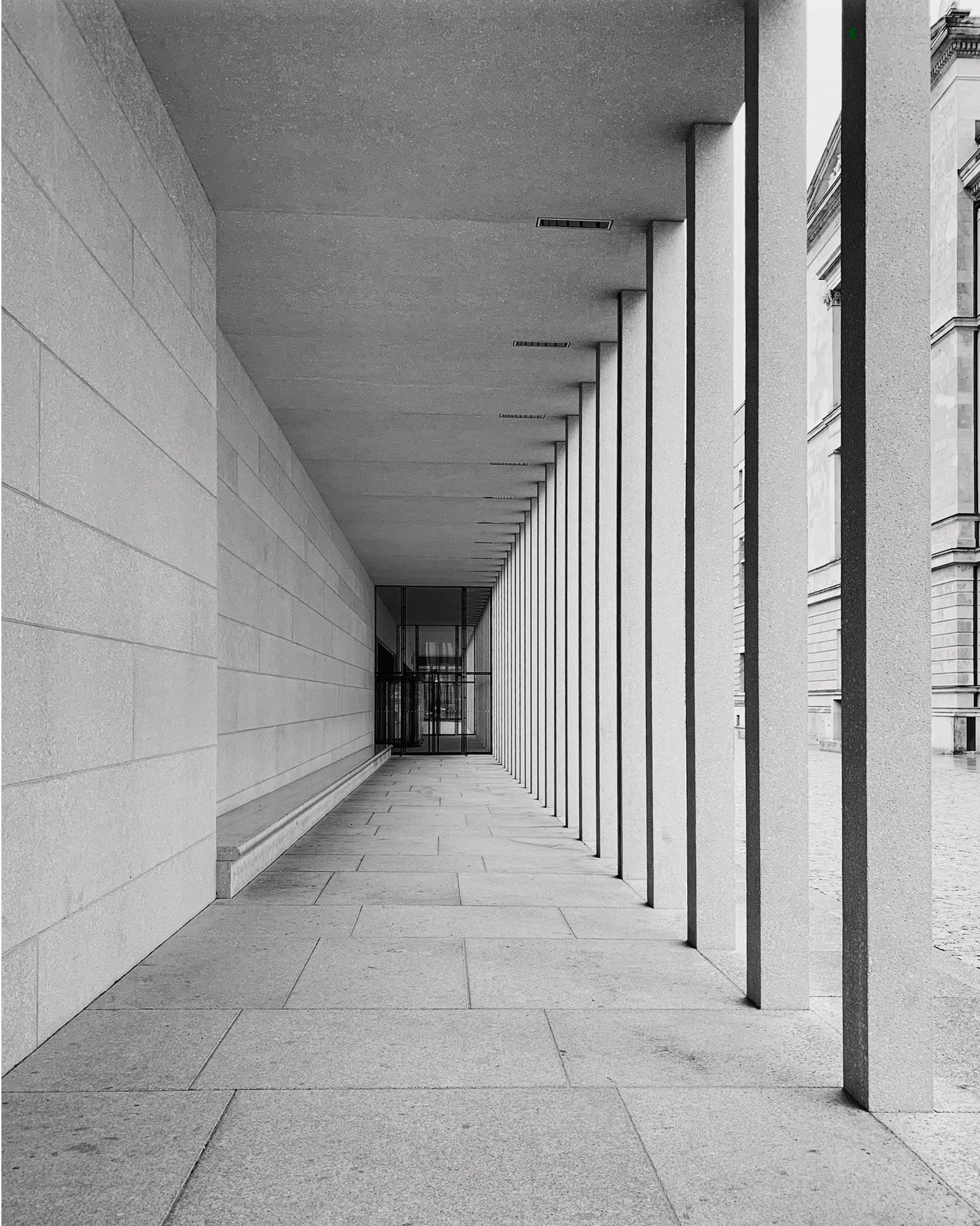 Durable granite exterior flooring on a long covered architectural walkway with large-format stone pavers and colonnade columns