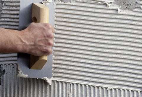 A coat of thinset being applied to a wall