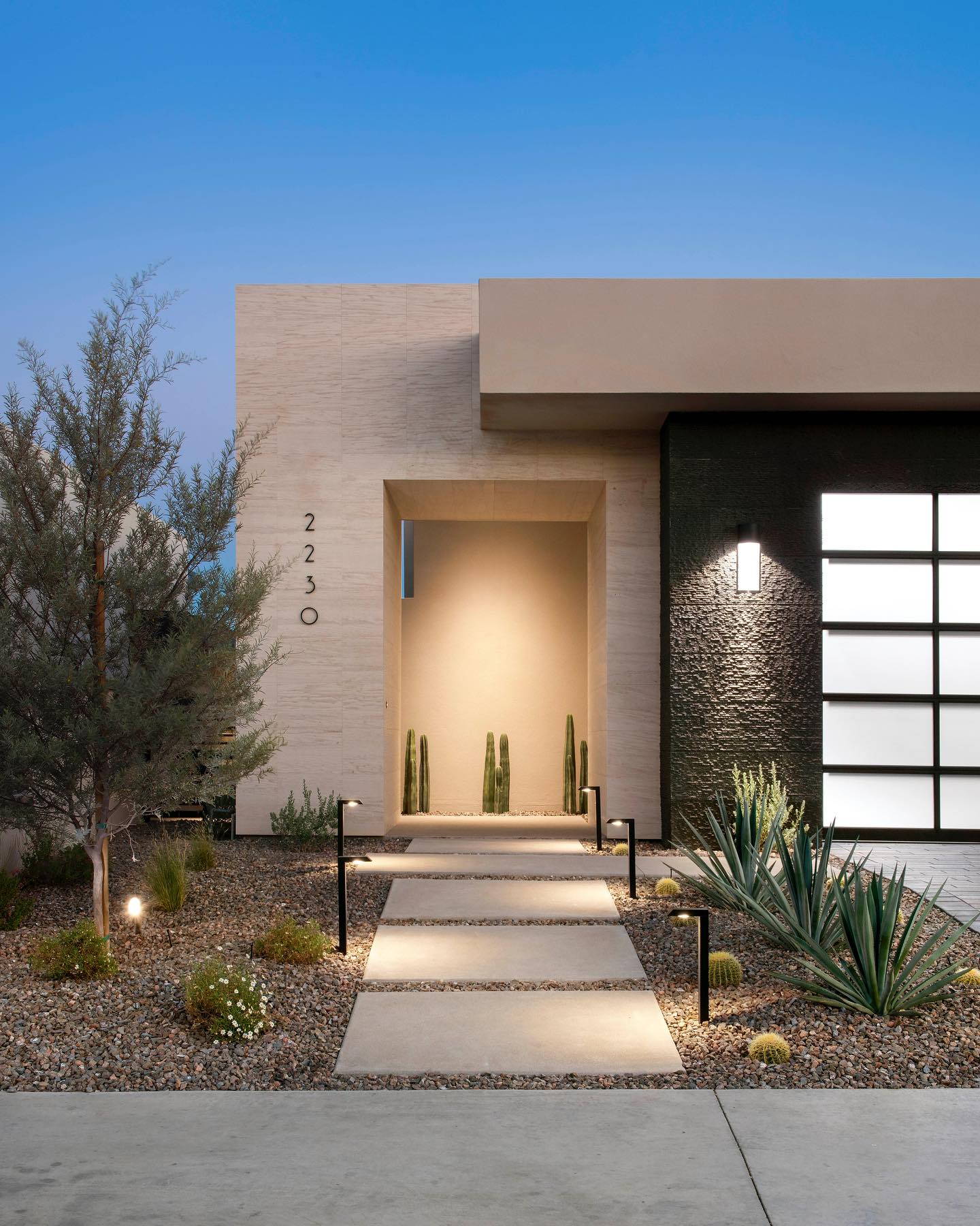 Front entrance stepping stone walkway ideas featuring large rectangular natural stone pavers set in gravel with integrated low-voltage pathway lighting, creating a clean, modern approach to a contemporary home entry with desert landscaping and architectural façade details